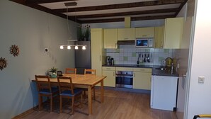 Una cocina compacta con comedor, vigas de madera en el techo y electrodomésticos básicos.