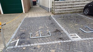 Un área de estacionamiento con pavimento de adoquines y topes metálicos.