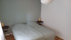 Un dormitorio con una cama, una mesita con lámpara y un aplique de pared.