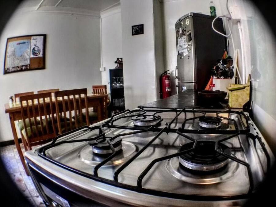 A kitchen with a gas stove, a refrigerator, and a dining area with chairs.