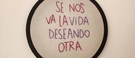 Un bordado circular con texto sobre un fondo beige, enmarcado por un borde negro.