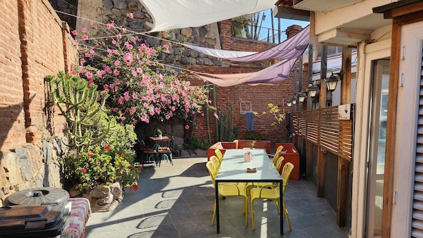 A patio with a table and chairs, surrounded by plants and a brick wall. - La Casa Piola (Valparaiso)
