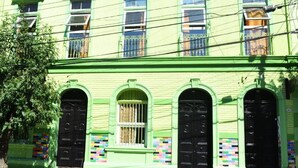 Un edificio con fachada verde, varias ventanas y puertas negras.