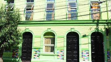 A building with a green facade, multiple windows, and black doors.