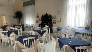 A dining area with tables and chairs, a chandelier, and a piano. - Room-viareggio Rooms Facing the sea (Viareggio)