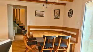 A dining area with a wooden table and chairs, a bench, and a staircase in the background. - La Maison du Vieux Bourg (Perrier)
