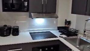 Een moderne keuken met donkere kastjes, een magnetron, een fornuis en een spoelbak.