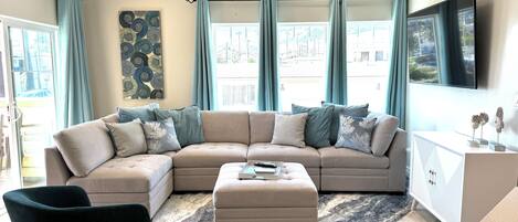 A modern living room with a sectional sofa, a coffee table, and a ceiling fan.