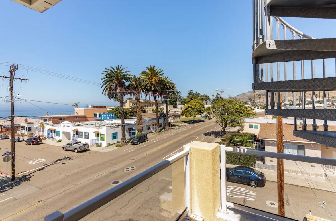 A street view with buildings, palm trees, and a clear sky.