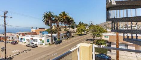 A street view with buildings, palm trees, and a clear sky.