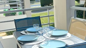 A covered outdoor dining area with a table set for four, surrounded by chairs with blue cushions. - Quiet apartment with swimming pool, near the sea, located in the Golf de Pornic. (Pornic)