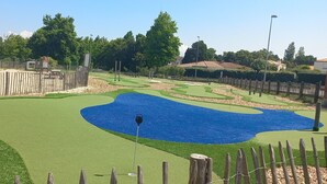 A golf course with a water hazard, wooden fences, and a clear sky. - Quiet apartment with swimming pool, near the sea, located in the Golf de Pornic. (Pornic)