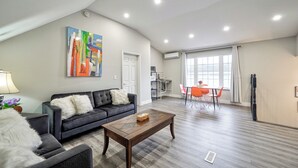 Un salon moderne comprenant un canapé, une table basse et un coin repas avec des chaises.