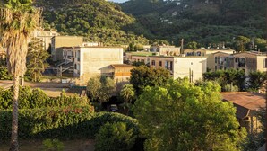 A residential area with buildings surrounded by lush greenery and hills in the background. - Relais Mirage Sorrento (Sorrento)