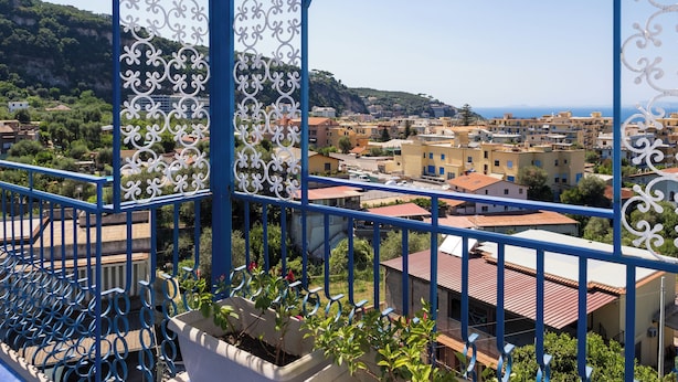 A balcony with a view of a coastal town, featuring buildings with red roofs and a clear sky. - Relais Mirage Sorrento (Sorrento)