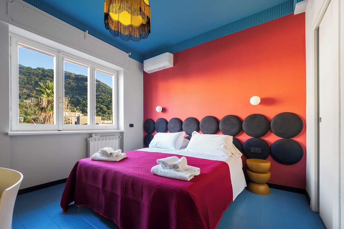 Een moderne hotelkamer met een groot bed, uitzicht op de omgeving en een opvallend wandontwerp.