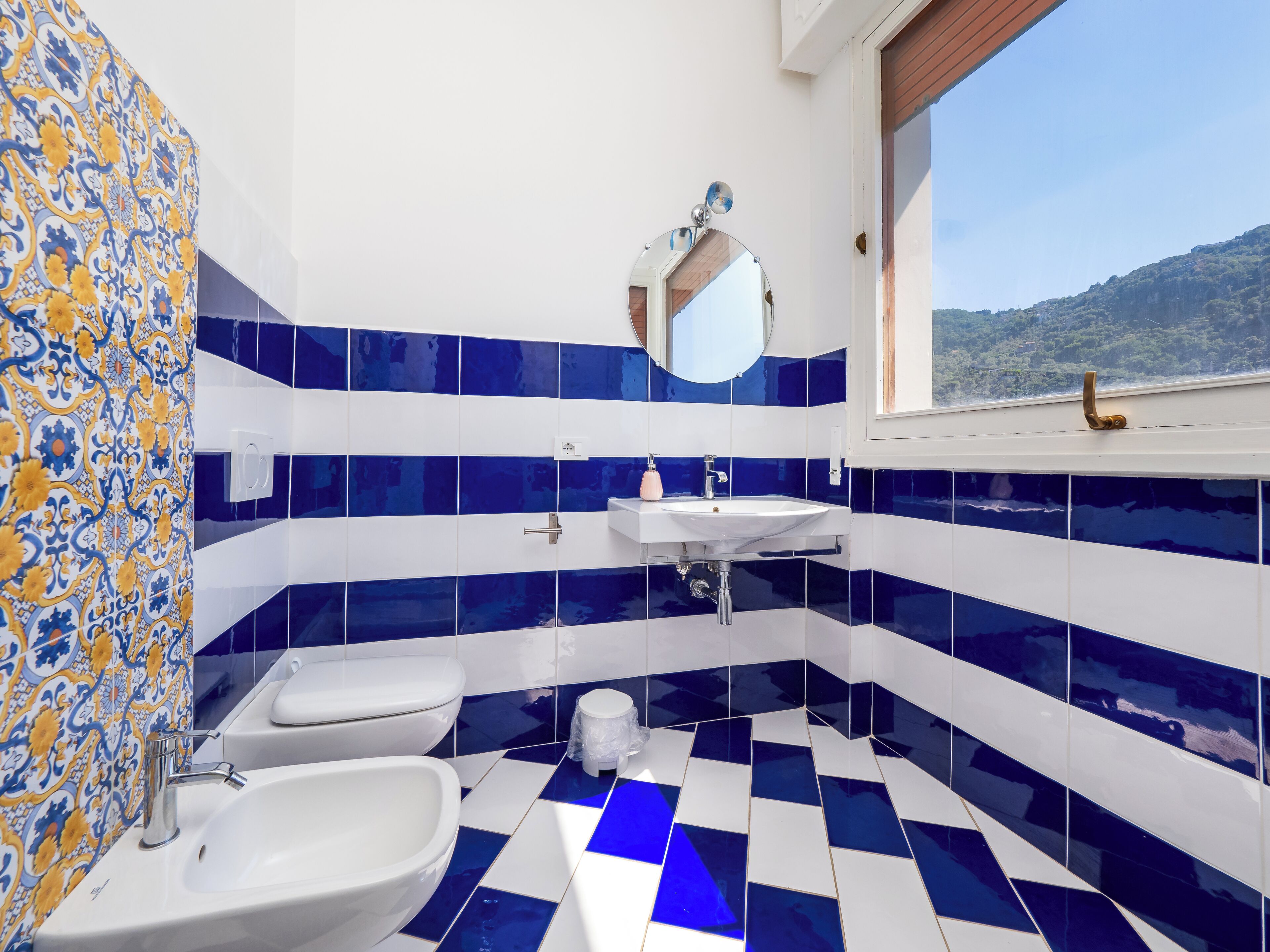 A bathroom with a checkered floor, a sink, a toilet, and a mirror.