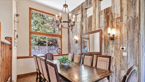 A dining room with a wooden table, chairs, and a chandelier.