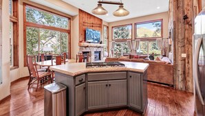 A spacious kitchen with a large island, wooden cabinetry, and a stone countertop.