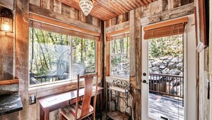 A rustic wooden cabin interior with a wooden desk, chair, and bench.