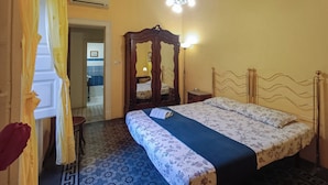 Un dormitorio con cama, un armario de madera y un baño que se ve a través de una puerta abierta.