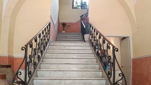 Una escalera de mármol con barandilla de hierro negro que conduce a un piso superior. La palabra "SALVE" está grabada en el suelo.