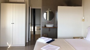 A bedroom with a bed, a white wardrobe, a mirror, a sink, and a ceiling fan. - Evreti DREAMHOUSE Stone House With Private Pool & Sea View. A Paradise on Earth! (CHMJ+HVW Evreti, Greece)