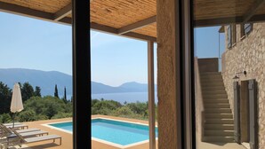 A modern villa with a pool, wooden deck, and a view of mountains.