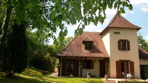 A two-story house with a pitched roof, a small balcony, and a well-maintained lawn. - Chambre La Terrasse (Sarliac-sur-l'Isle)
