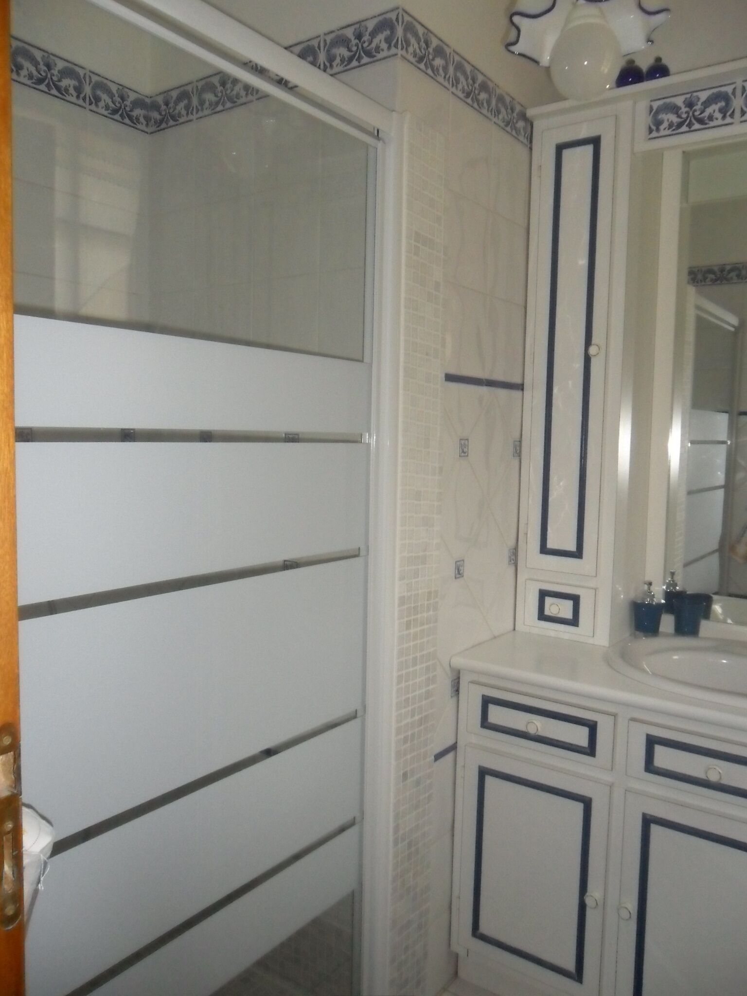 Ein Badezimmer mit weißem Waschbecken, Spiegel und Schränken.