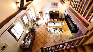 A dining area with a wooden table and chairs, a piano, and a staircase with a wooden railing. - Chambre La Terrasse (Sarliac-sur-l'Isle)