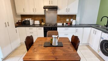 A modern kitchen with white cabinets, a wooden dining table, and a built-in washing machine.
