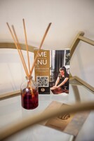 Una botella de vidrio con pajitas de caña, un folleto con un código QR y un cuadro con la imagen de una persona en un spa.