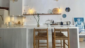 Une cuisine moderne avec un îlot central, des chaises en bois et un luminaire suspendu.