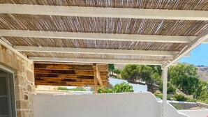 Un espace extérieur aménagé avec une table et des chaises, des murs en pierre et une pergola en bois.