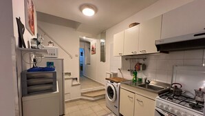 Une cuisine de taille réduite équipée d’un lave-linge, d’une cuisinière et d’un évier.