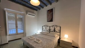 Une chambre à coucher avec un lit, une table de chevet, une lampe, un climatiseur et une fenêtre.