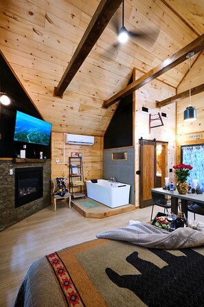 A wooden interior with a fireplace, a television, a bathtub, and a dining area.