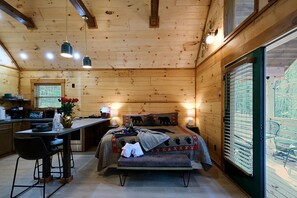 A cozy cabin with a wooden interior, a dining area, and a bed with a bear-themed blanket. - Fall Hidden Gem | Fireside Jacuzzi + Hot Tub (Sevierville)