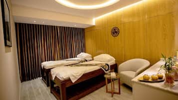 A hotel room with a wooden bed, a small round table, a chair, and a wall-mounted TV.