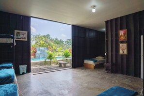 A spacious room with a large sliding glass door leading to a pool area. - Root Wellness Arenal (La Tigra)