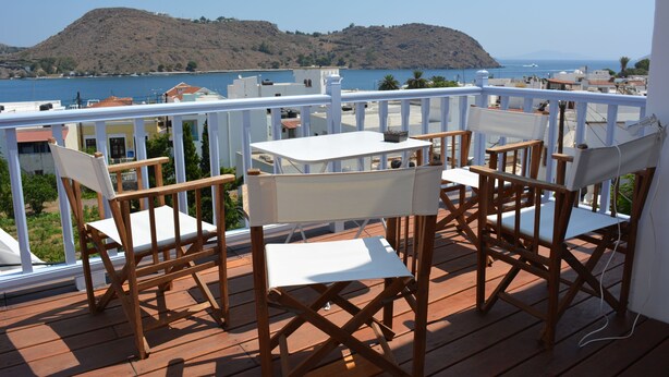 Eine Holterrasse mit Tisch und Stühlen mit Blick auf ein Gewässer und Hügel.