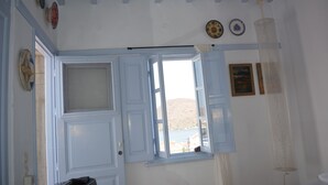 Ein Zimmer mit großem Fenster, einer Tür und einer wandmontierten Leuchte.