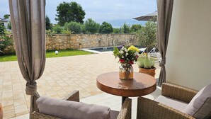 A patio with wicker furniture, a round wooden table, and potted plants. - Apartments with Shared Pool Casa Bianca (Kanfanar)