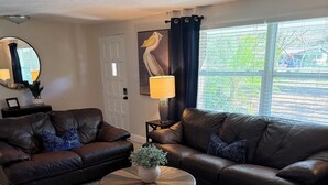 A living room with two brown leather sofas, a round wooden coffee table with a vase, a mirror, a lamp, and a window with blinds. - 2 separate homes, each 3-bed 2 bath one on Lake and are only a 5-min. car ride. (Lutz)