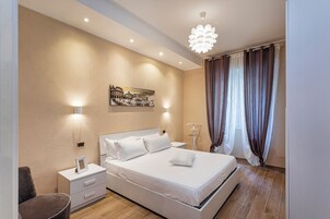 A modern bedroom with a large bed, bedside tables, a wall-mounted light, and a ceiling light fixture.