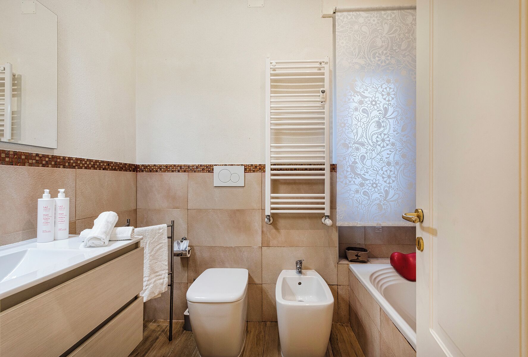 Un baño con bañera, inodoro, bidé y un perchero para toallas.