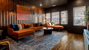 Een moderne woonkamer met een modulaire bank, een salontafel en een groot abstract schilderij aan de muur.
