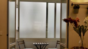 A dining area with a table, chairs, and a view through a frosted glass door.