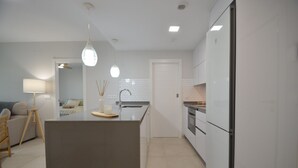 Une cuisine moderne avec des meubles blancs, un îlot central et des luminaires suspendus.